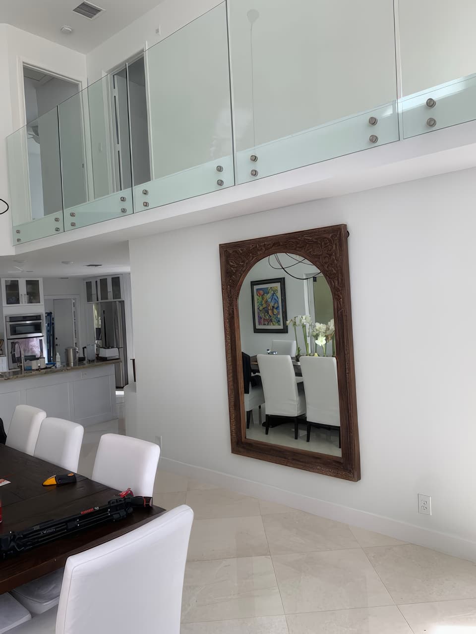The glass balcony rail above the dining area, with a large carved wood mirror on the wall below.